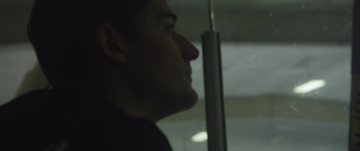 A man comes to the glass at the hockey rink and looks at the ice