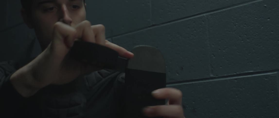A young man applying black hockey tape to a stick blade with his hands