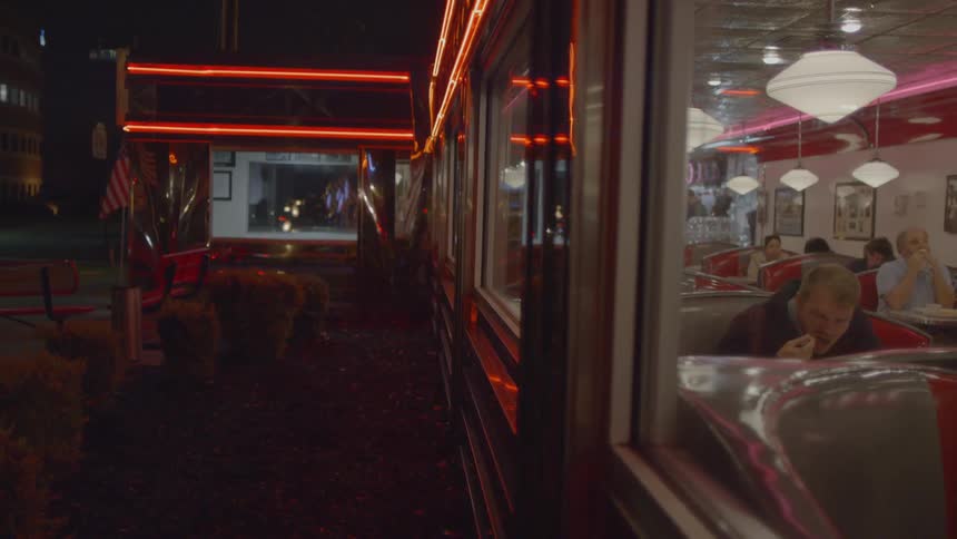 Neon lights shine over the windows of a city storefront at night