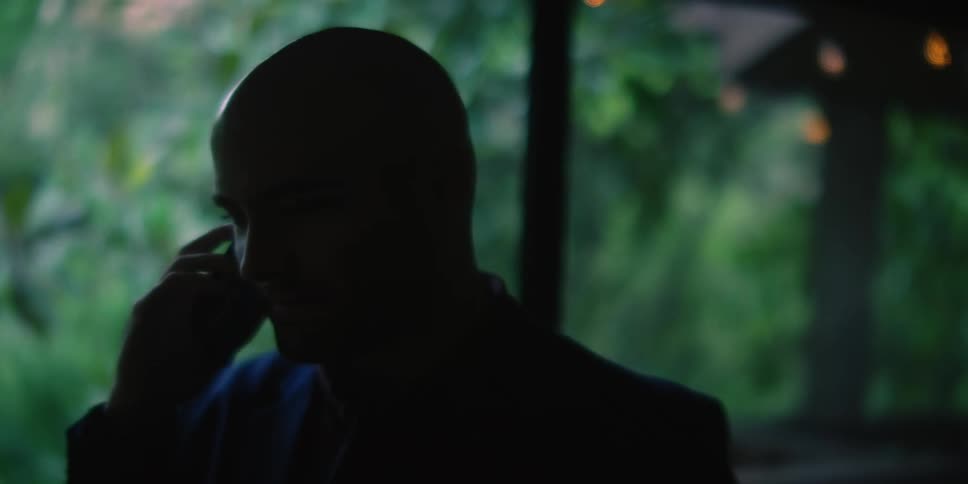 A bald man with a phone to his ear is talking