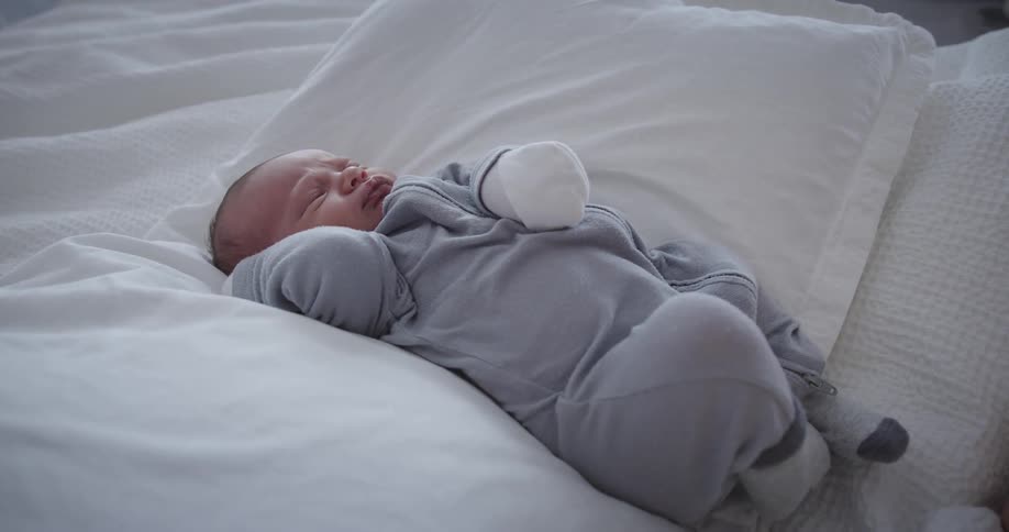 A baby sleeping on the bed at midday