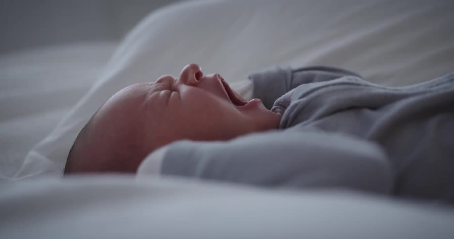 Newborn baby lying down sleeping and yawning