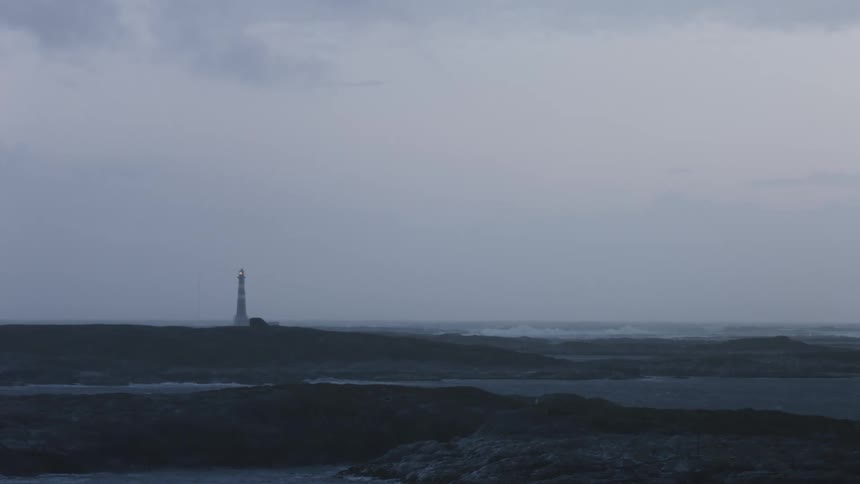 A lighthouse on a peninsula with its light turned on