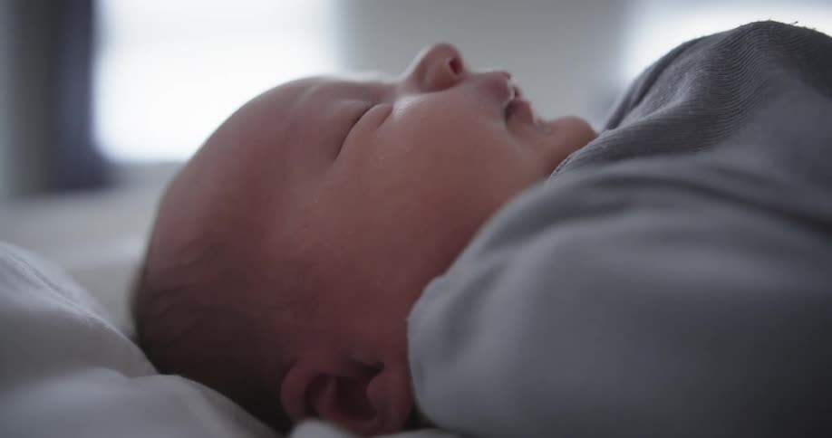 Baby lying on its back moves in its sleep