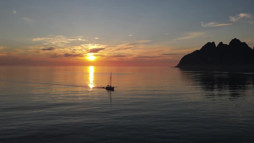 View of a boat in the open sea with the sunrise on the horizon