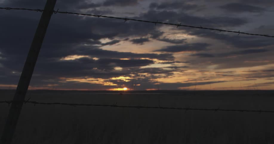Agricultural field enclosed with barb wires at sunset