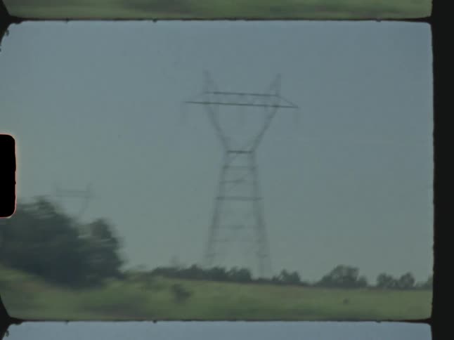 Power lines on a roadside in the middle of a field on a bright sunny day