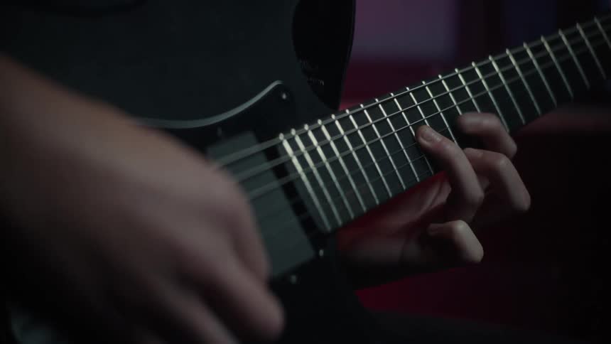 Hands of a person playing notes on a guitar