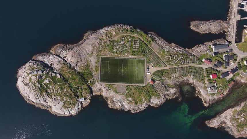 Drone view of a soccer field on a peninsula surrounded by the ocean