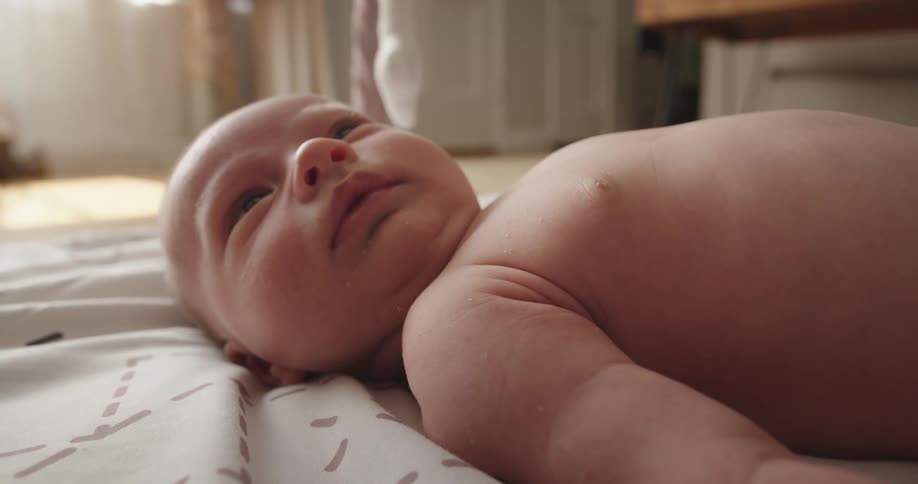 Baby lies on the floor indoors looking up
