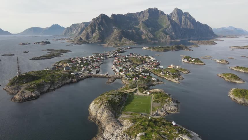 Aerial of buildings and a football pitch on an island at midday