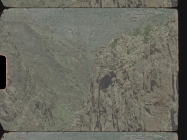 Structure stands on edge of cliff in craggy mountains