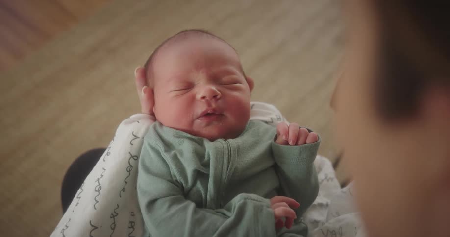Hand holding a baby on their legs and using their hands to help clean the babys mouth