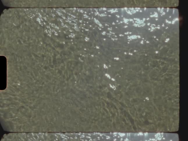 Close up of running water in a shallow area with the sun reflecting off the surface