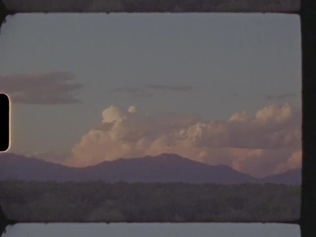 Cumulus clouds move behind mountains across the sky