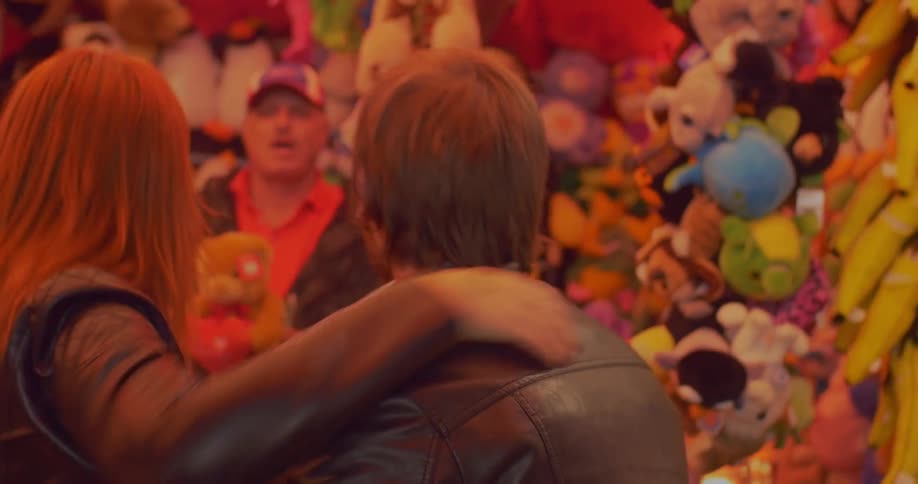 Man and woman hug and are handed a prize at the fair