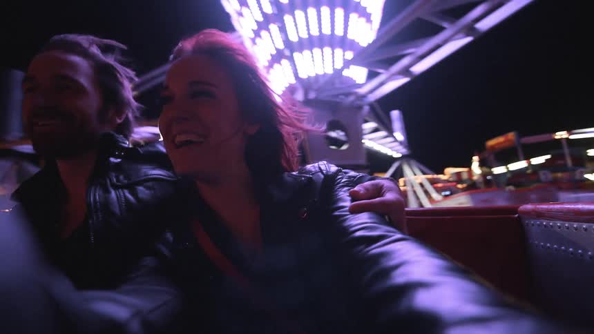 A man and woman ride a carnival ride