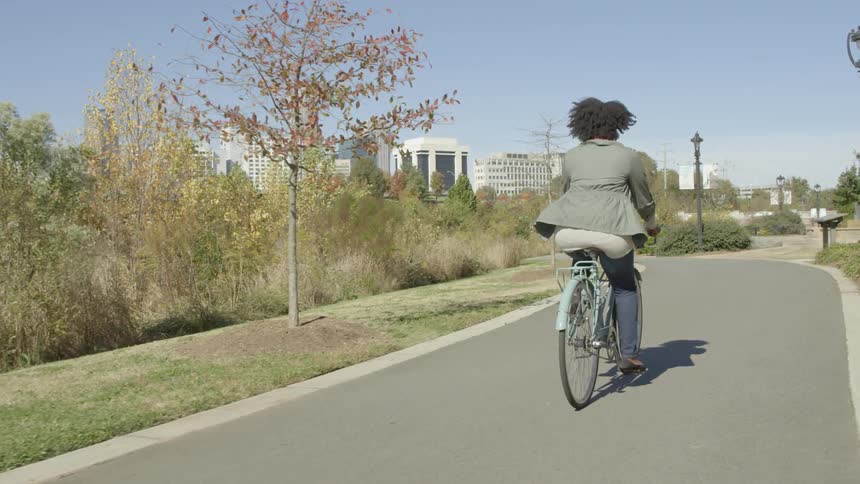 Woman rides her bike through a park