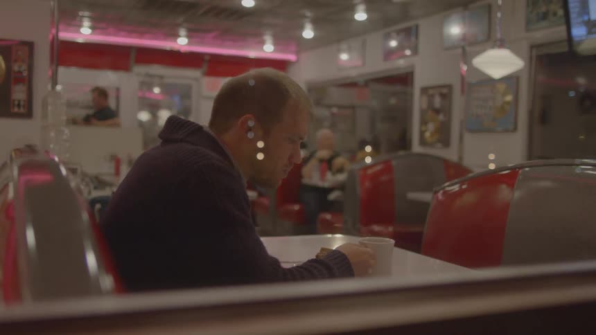 A man is sitting by himself in a diner eating