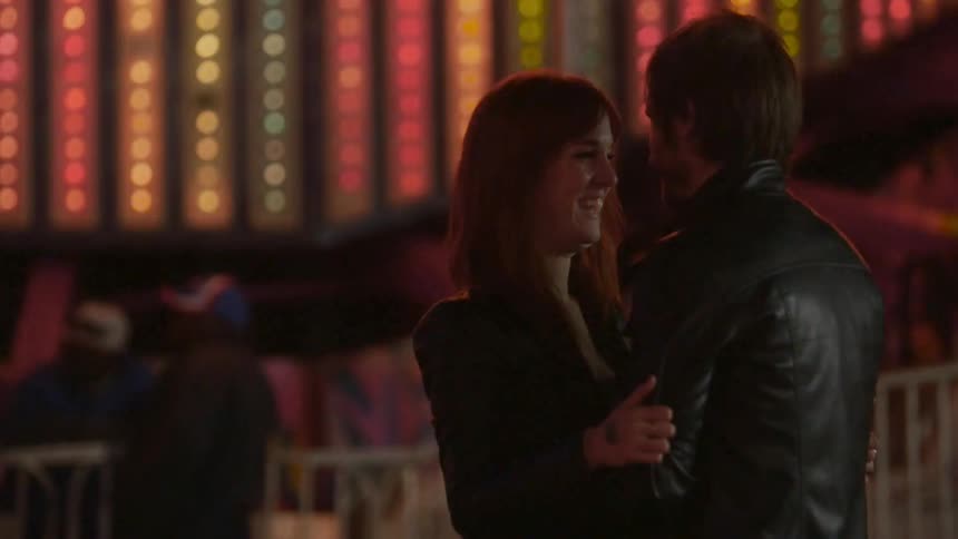 A man and woman hold each other at a carnival