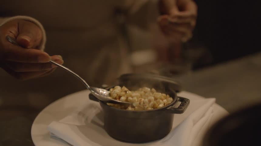 A woman takes a spoonful of hot food and blows on it
