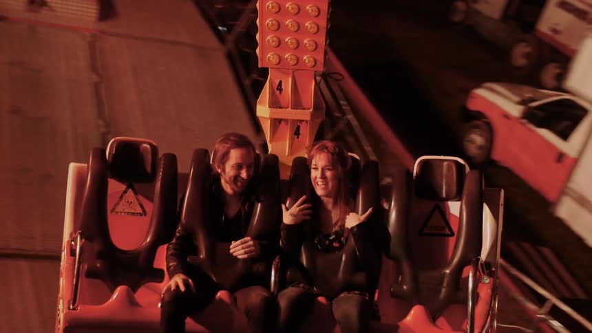 Man and woman ride a fair ride together at night