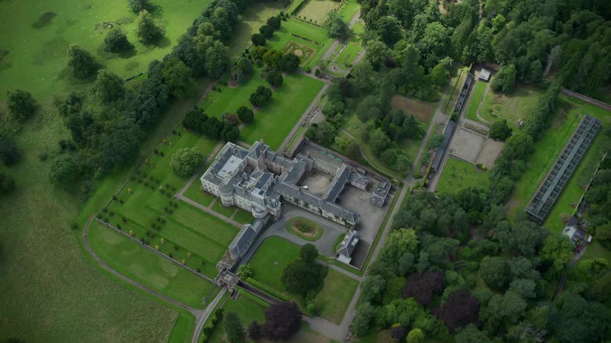 Aerial view of a mansion in an open area with abundant vegetation