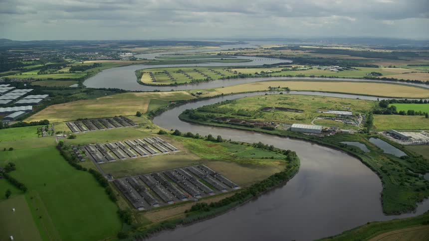 A region with a curved river passing through grassy land with some buildings