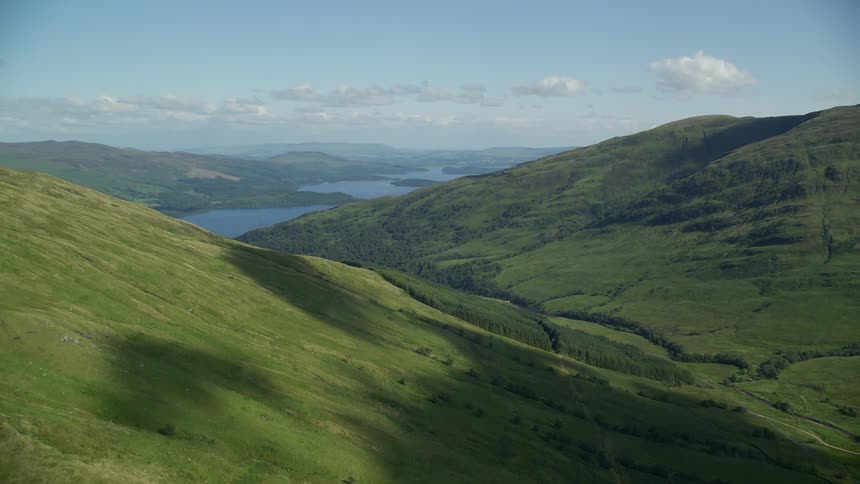 Wide open view of grass covered mountains with a river in the background