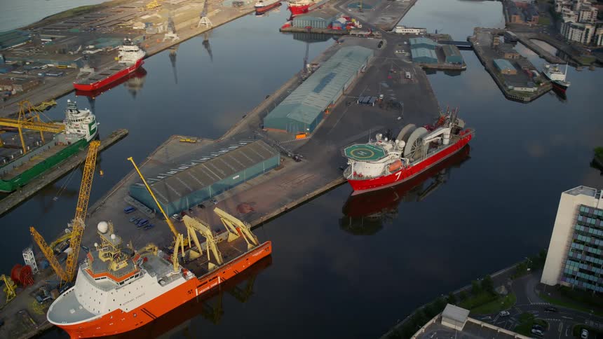 Cargo ships are docked at the loading docks with buildings along the coast