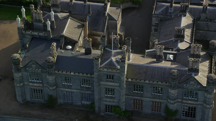 An aeria view of a constriction that looks like a castle on a lawn and backs a forest