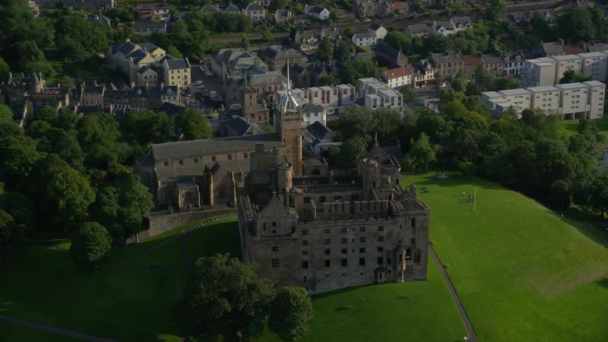 Aerial view of a castle in front of a river next to the city