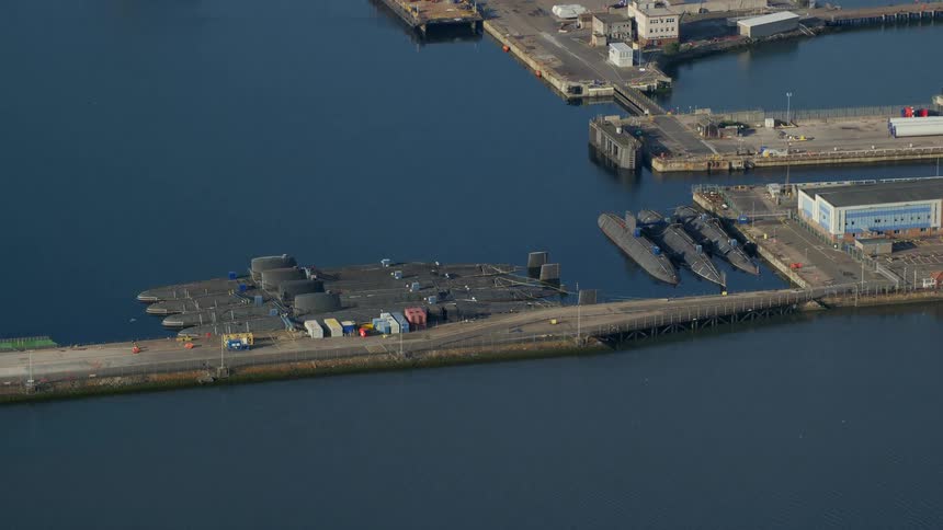 Drone view of submarines docked at a marina on the water on a bright sunny day