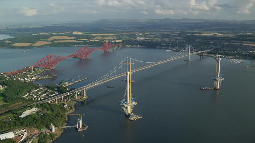 Aerial of bridges going over a large river connecting two pieces of land with neighborhoods on either side