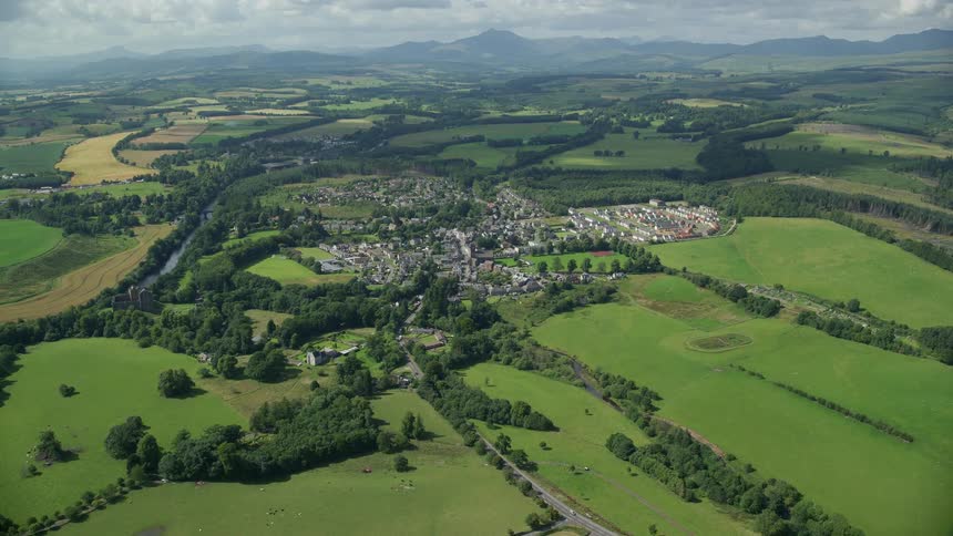 Aerial of a wide open landscape covered in grasslands and trees with a rural village among the trees