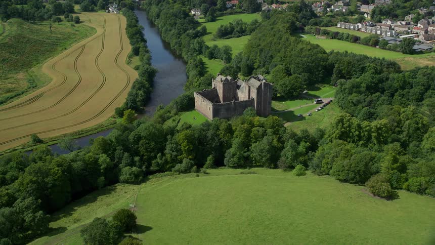 A castle sits along a river near a neighborhood