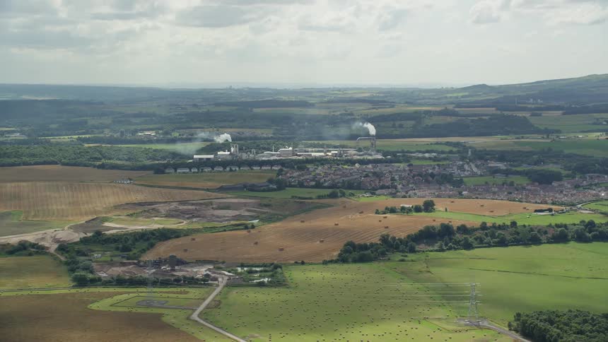 Aerial view of a rural area with factories emitting smoke in the background