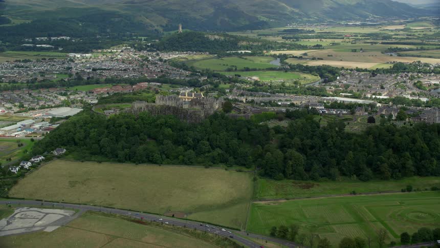 Aerial of a field and trees with a road leading to villages with houses across the land