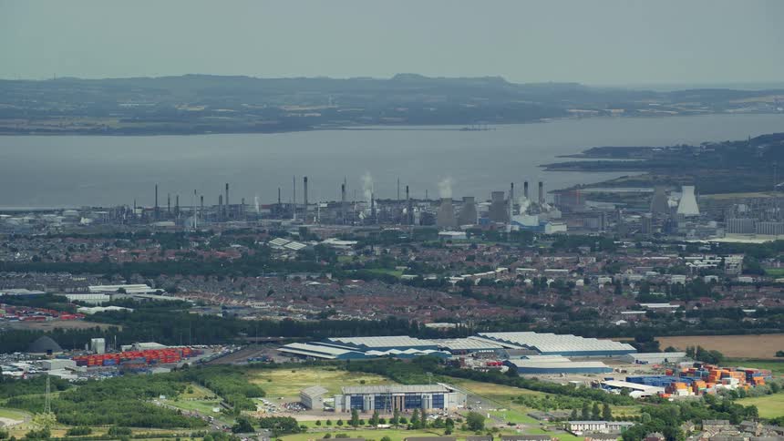 A city with several factories on the edge of a river producing a lot of smoke