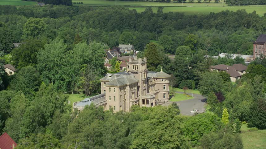 Aerial of the castle in a residential neighborhood with greenery on the outskirts of the city