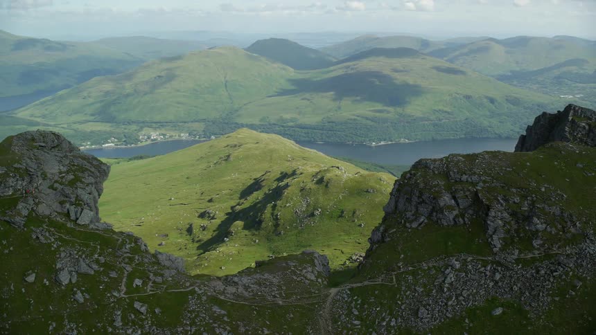 Aerial of a mountain region with grass covering the hillsides and a river down below