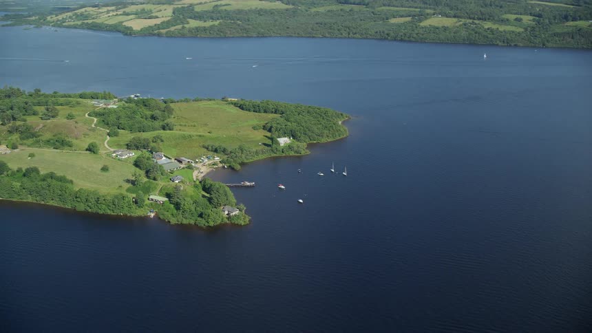 Aerial of a river with boats parked near land with lush green grass and trees
