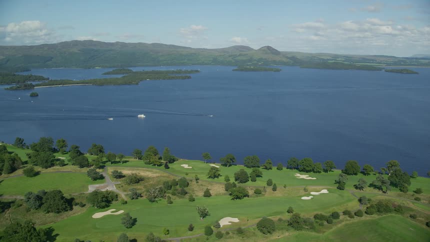 A golf course lies next to a large mountain lake with several islands