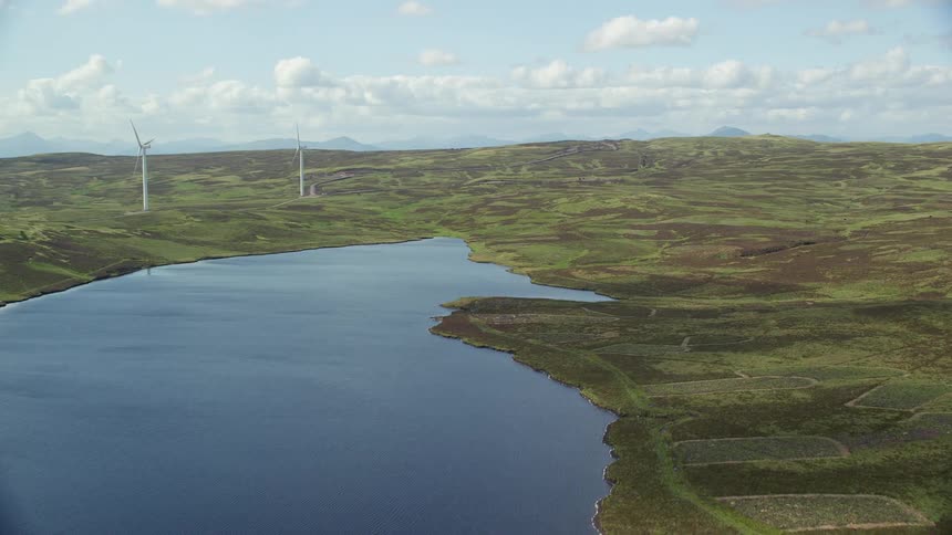 Aerial of flat landscape with wind farms and lake