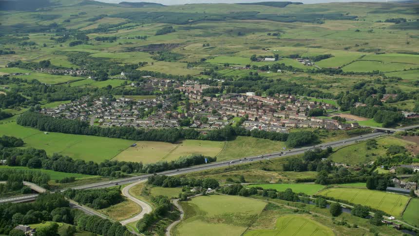 A small rural town in grassy fields next to a highway