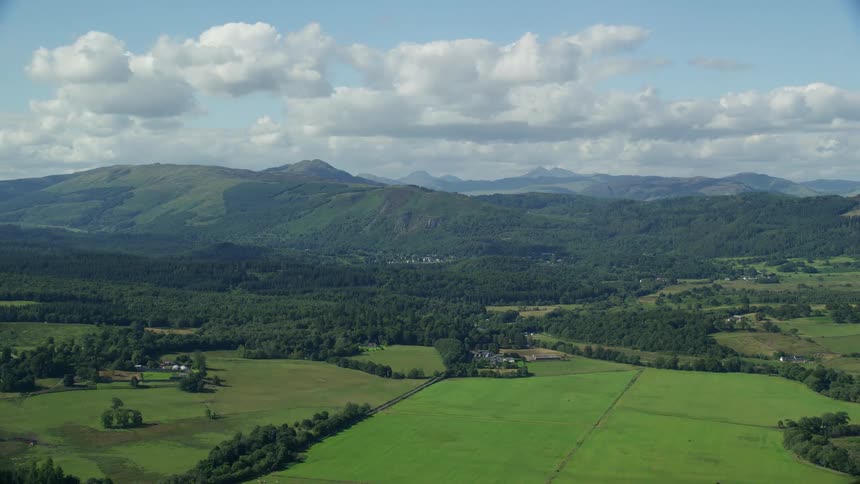 Aerial view of a lush rural area with a mountain range in the background