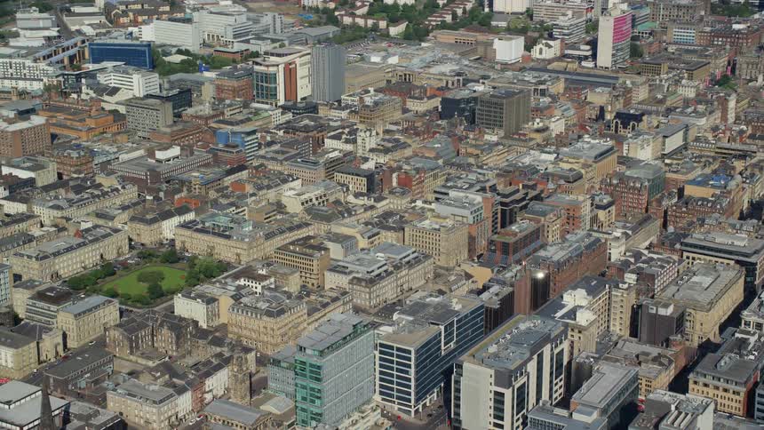 Aerial of a city with many buildings close together with a small park among them during the day