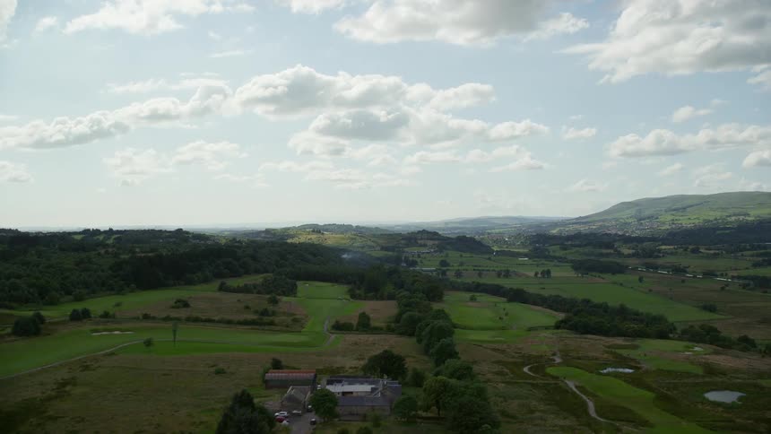 Aerial of the end of an airstrip revealing a grass covered land in a rural area on a bright sunny day