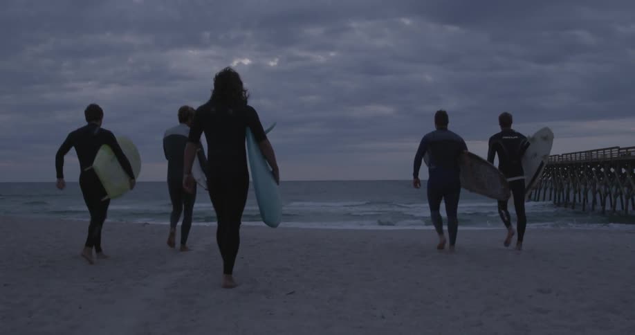 Group of men carrying their surfboards towards the water