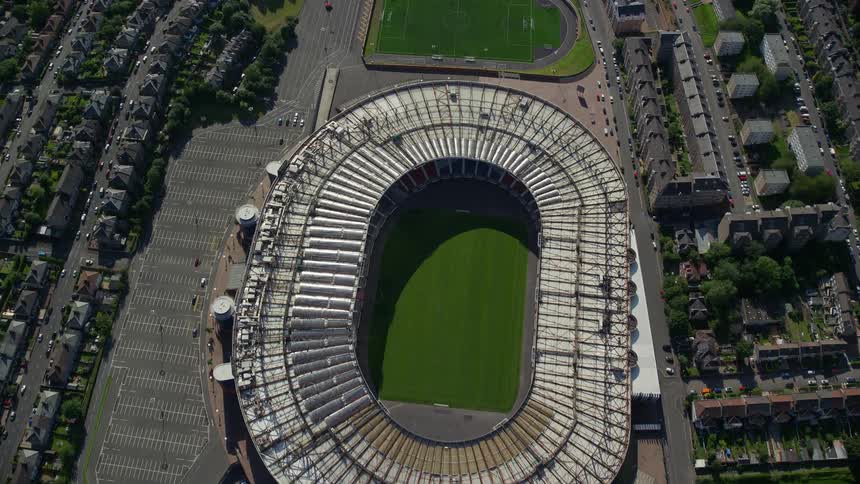 Aerial of an oval stadium with a large field in the middle and a soccer field on the outside of it